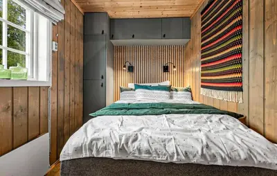 a bedroom with a large bed in a wooden wall at 2 Bedroom Gorgeous Home In Svingvoll in Svingvoll