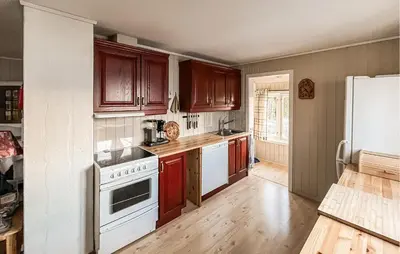 a kitchen with wooden cabinets and white appliances at 2 Bedroom Awesome Home In Vanvikan in Vannvikan