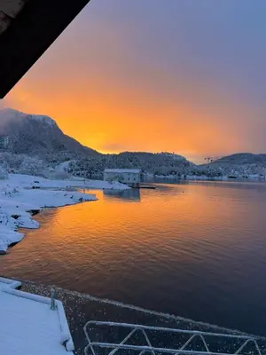 a sunset over a body of water with snow at Amundøya Seaside in Kristiansund