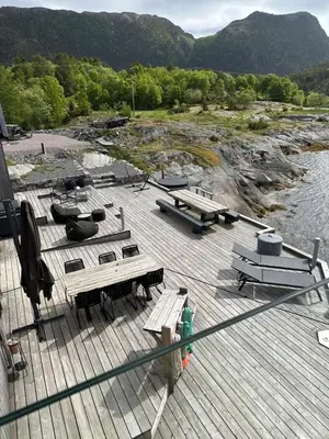 a deck with picnic tables and benches next to a river at Amundøya Seaside in Kristiansund