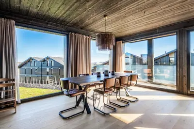 a dining room with a table and chairs and large windows at Kikut Alpin Lodge 2204 in Hol