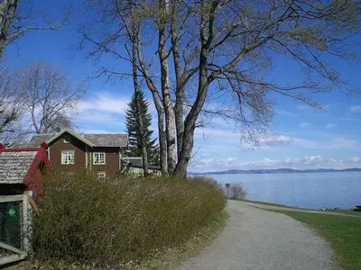 a house on the side of a road next to a lake at Koselig bolig med stor stue, 10 min from Solsiden! in Trondheim