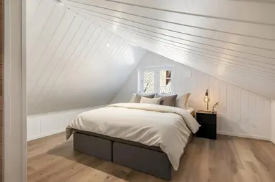 a white attic bedroom with a bed and a window at Historic Bergen House with Sunny Terrace in Bergen