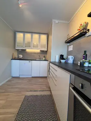 a kitchen with white cabinets and a black counter top at Midt i Raufoss, stor leilighet med hage in Raufoss