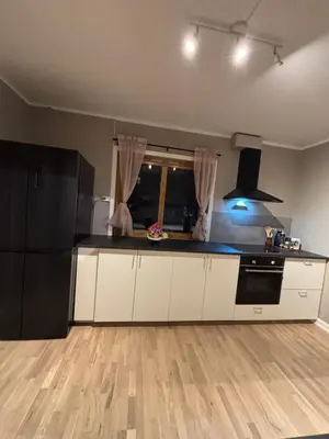 a kitchen with white cabinets and a black refrigerator at Midt i Raufoss, stor leilighet med hage in Raufoss