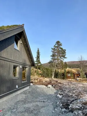 a house with a gravel driveway next to a building at Reno Hytta in Eggedal