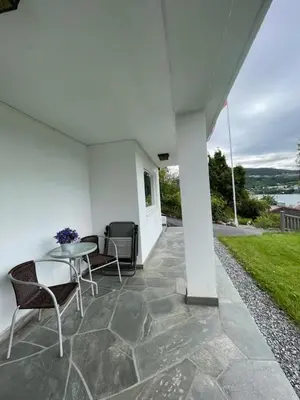 a patio with a table and chairs on a house at Solbakken, nice Apartment by the Sea in Ålesund in Ålesund
