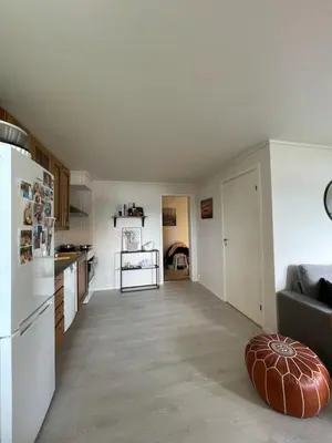 a kitchen with a white refrigerator and a living room at Solbakken, nice Apartment by the Sea in Ålesund in Ålesund
