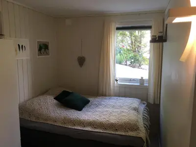 a small bedroom with a bed and a window at Solbakken, nice Apartment by the Sea in Ålesund in Ålesund