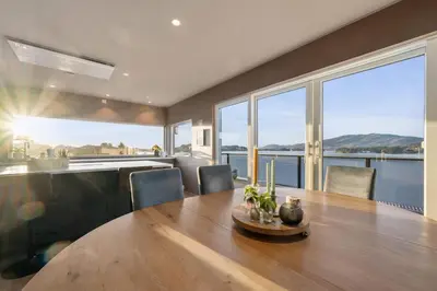 a dining room with a table and large windows at Luxury Seafront Villa with Panoramic Views in Veland