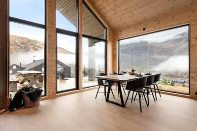 a dining room with a table and chairs and large windows at Skarhaug Panorama Lodge in Stranda