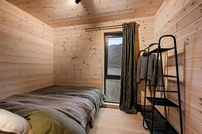 a log cabin bedroom with a bed and a window at Skarhaug Panorama Lodge in Stranda