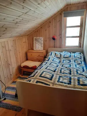 a bedroom with a bed in a wooden room at Familiehytte på Botn, Vågslid til leie in Botn