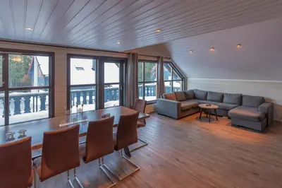 a living room with a couch and a table and chairs at Bakkebyvegen 22A in Trysil