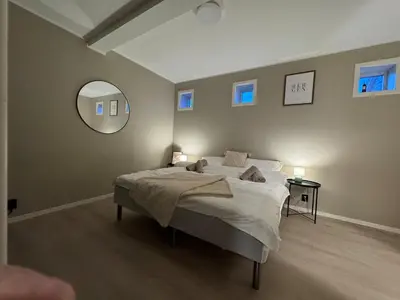 a bedroom with a large bed and a mirror at Sandvik's stuen in Bergen