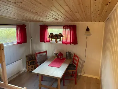 a table and chairs in a small room with red windows at Nedre Flaata Seter in Nørdstebø