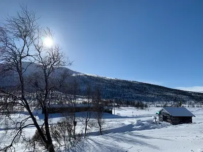 a cabin in a snow covered field with a mountain at Nedre Flaata Seter in Nørdstebø