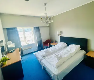 a bedroom with a large bed and a chandelier at Suldal Hotell in Sand