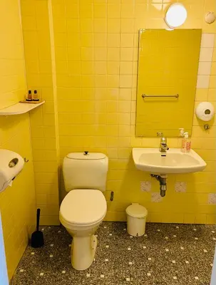 a yellow bathroom with a toilet and a sink at Suldal Hotell in Sand