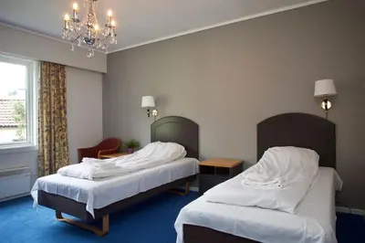 a hotel room with two beds and a chandelier at Suldal Hotell in Sand
