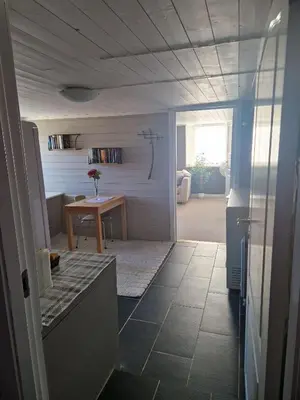 a room with a table and a door to a room at Cosy living room, bedroom and bathroom and kitchen area in Kolavåg