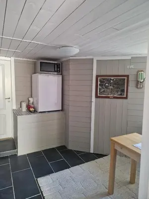 a kitchen with a white refrigerator and a table at Cosy living room, bedroom and bathroom and kitchen area in Kolavåg
