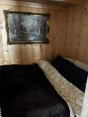 a bed in a room with a picture on the wall at Cozy Off-Grid Cabin - No Power, No Running Water