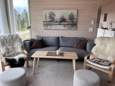 a living room with a blue couch and two chairs at Hytte Hummelfjell, Os in Os