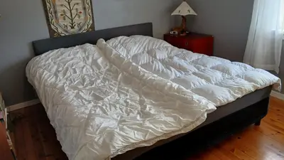 an unmade bed in a bedroom with a wooden floor at The house by the waterfall in Breim