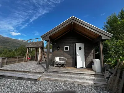 a small cabin with a bench on a wooden deck at Lunvik - Flott hytte ved Nysætervatnet in Sykkylven