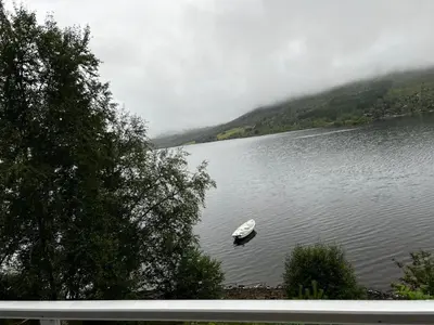 a boat in the middle of a lake in the mountains at Lunvik - Flott hytte ved Nysætervatnet in Sykkylven
