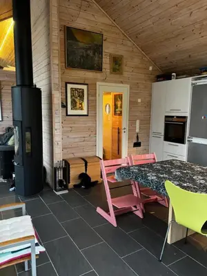 a room with a table and chairs and a stove at Lunvik - Flott hytte ved Nysætervatnet in Sykkylven