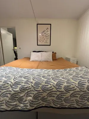 a bedroom with a bed with a blue and white blanket at Moderne leilighet med 2 soverom for jobb og ferie in Raufoss