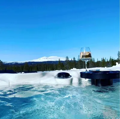 a hot tub with a glass of wine in the snow at Modern cabin with jacuzzi near Trysil alpine in Trysil