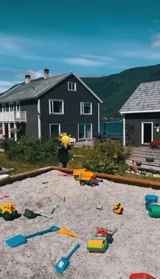 a pile of toys in the sand in front of a house at Private house on cider farm - fjord, beach & jetty in Sogndal
