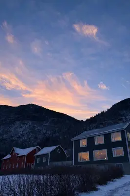 a building with snow on the ground next to houses at Private house on cider farm - fjord, beach & jetty in Sogndal