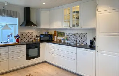 a white kitchen with white cabinets and a sink at Beach Front Home In Rovde With Wifi in Rovde