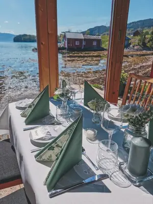 a table with plates and glasses on top of it at Fjordside Boathouse Hardanger in Kvam