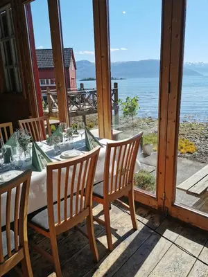 a table on a porch with a view of the ocean at Fjordside Boathouse Hardanger in Kvam