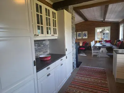 a kitchen with white cabinets and a living room at Kilodden, Lakeside Mountain Cabin with Stunning Views in Tuddal
