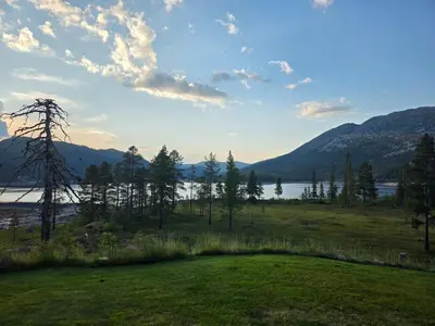 a field with a view of a lake and mountains at Kilodden, Lakeside Mountain Cabin with Stunning Views in Tuddal
