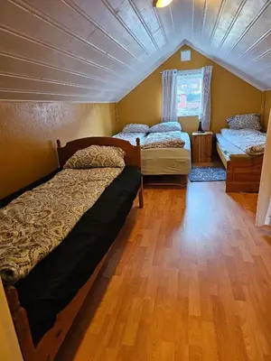 a bedroom with two beds and a wooden floor at Charming and cozy house in Vindafjord in Dørheim