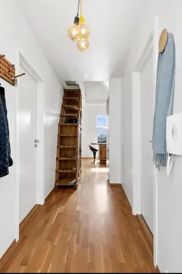 a hallway of a home with white walls and wooden floors at Topp floor apartment with one bedroom & a loft in Ålesund