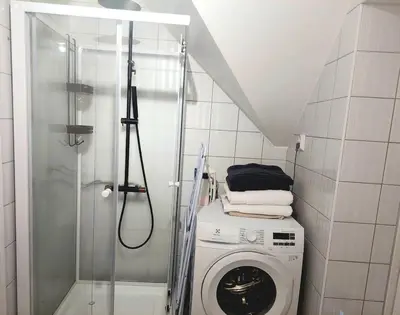 a bathroom with a washing machine and a shower at Topp floor apartment with one bedroom & a loft in Ålesund