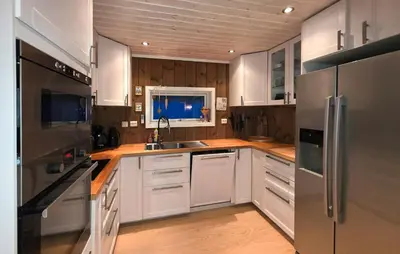 a kitchen with white cabinets and a stainless steel refrigerator at Cozy Home In Rauland With Sauna in Rauland