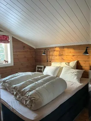 a large bed in a room with a wooden wall at Family-Built Cabin At The Three Line in Eggedal
