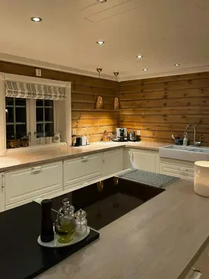 a kitchen with wooden walls and white cabinets and a sink at Family-Built Cabin At The Three Line in Eggedal