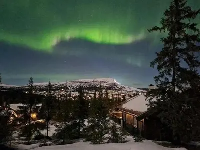 an aurora is dancing in the sky over a house at Cabin With Sauna By Ski Trails In Skeikampen in Svingvoll