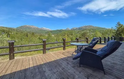 a patio with two chairs and a table on a deck at Cosy Cabin With Jacuzzi Right By The Ski Slope in Norheimsund