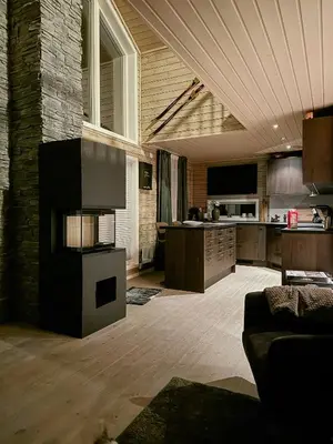 a living room with a fireplace and a kitchen at Mountain Cabin With Sauna Atop Fageråsen in Trysil